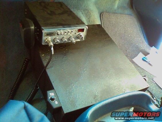 CB radio mounted on a black platform inside a vehicle, with a microphone attached