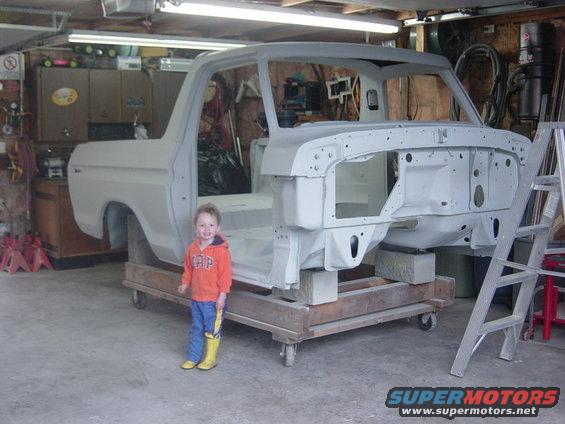 1979 Ford Bronco body, unpainted, on cart with child