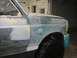 1996 Ford Bronco - Side view of a 1996 Ford Bronco undergoing body repair, showing primer and filler on the fender and door.