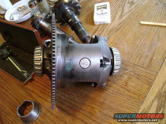 differential carrier, gears, caliper, and cigarette pack on wooden table