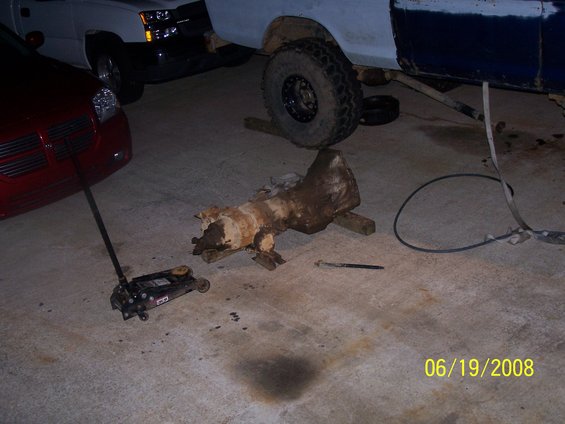 Red car and a blue and white truck with a transmission on the ground