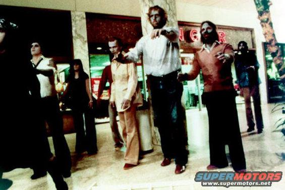Group of people walking in a mall, some with outstretched arms