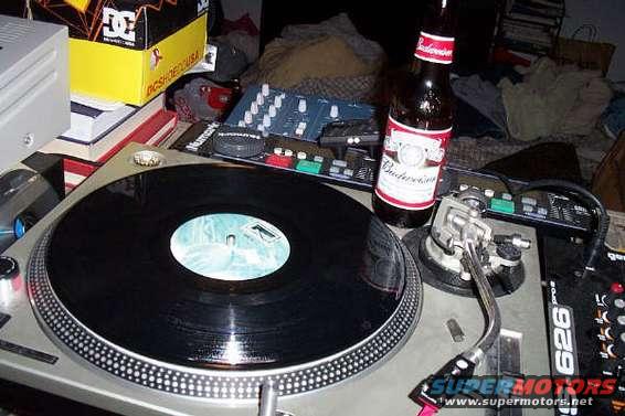 Turntable with vinyl record, DJ mixer, and Budweiser bottle