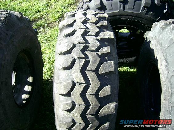 Several off-road tires, one with aggressive tread pattern in focus