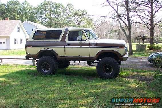 1979 Ford Bronco parked on grass, side view. Beige and brown two-tone paint, lifted suspension with large tires