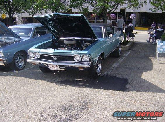 Light blue 1969 Chevrolet Chevelle SS coupe with hood open, showing engine, parked on asphalt