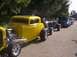 1970 Ford Ranchero - Several custom cars are lined up on a paved surface, with trees in the background.