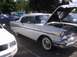 1970 Ford Ranchero - A white 1957 Chevrolet Bel Air is displayed with its hood open, alongside other vehicles at an outdoor event.