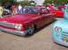 1970 Ford Ranchero - A classic red Chevrolet Impala is displayed at an outdoor car show with other vehicles.