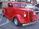 1970 Ford Ranchero - A bright red 1935 Ford pickup truck is displayed outdoors with other classic vehicles.