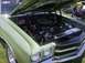 1970 Ford Ranchero - The front of a light green 1970 Ford Ranchero is visible with the hood open, revealing its V8 engine and chrome details.