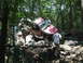 1967 Ford Bronco - Off-road vehicles tackle challenging rocky terrain in a wooded area.