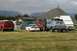 1990 Chevrolet Suburban - A group of vehicles and tents are set up in a field, with a large pile of gravel in the background.