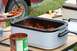 1990 Chevrolet Suburban - Spaghetti is served from a crockpot next to a red vehicle at an outdoor gathering.