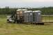 1990 Chevrolet Suburban - A white flatbed truck transports several portable toilets on a trailer through a grassy field.