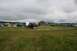 1990 Chevrolet Suburban - An outdoor event with multiple vehicles, tents, and RVs set up in a grassy field under a cloudy sky.