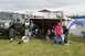 1990 Chevrolet Suburban - A lifted SUV is parked at an outdoor event with a vendor tent and camping tents in the background.