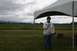 1990 Chevrolet Suburban - A woman stands under a tent holding a microphone, with a cloudy sky and distant mountains in the background.