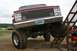 1990 Chevrolet Suburban - This lifted red truck, possibly from the 1980s, features a prominent chrome grille and large off-road tires. Another vehicle is visible in…