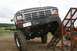 1990 Chevrolet Suburban - This heavily modified Ford truck is equipped for off-road challenges, with other vehicles in the background.