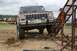 1990 Chevrolet Suburban - A red and silver Jeep Cherokee XJ, likely from the 1980s or early 1990s, is positioned near a metal ramp at an outdoor event.