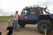 1990 Chevrolet Suburban - A blue off-road vehicle with a driver and passenger is parked while a person in an orange vest speaks to them.