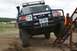 1990 Chevrolet Suburban - A blue Toyota FJ Cruiser navigates a sandy obstacle course with a person in an orange vest nearby.