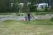 1990 Chevrolet Suburban - Two children stand in a grassy field, with several RVs visible in the distance.