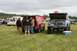1990 Chevrolet Suburban - A lifted pickup truck with its hood open sits in a grassy field next to another vehicle.
