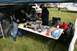 1990 Chevrolet Suburban - An outdoor event displays various automotive parts and accessories laid out on tables, with vehicles and campers visible in the distance.