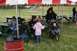 1990 Chevrolet Suburban - An outdoor gathering with people seated at picnic tables under a large tent, with a baby in a stroller nearby.
