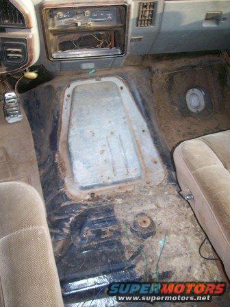 1988 Ford Bronco interior floor with exposed metal and dirty carpeting