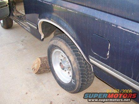 Dark blue SUV side view, rear wheel on log