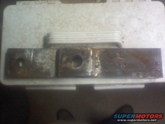 rusted metal bracket with two holes, one round and one square-ish