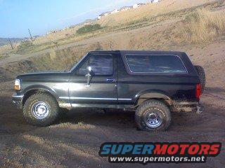 Dark green 1993 Ford Bronco SUV with a spare tire on the rear, parked on a dirt road