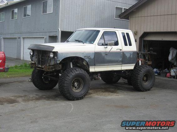 White and gray lifted 1990 Ford F-250 with large off-road tires parked in driveway