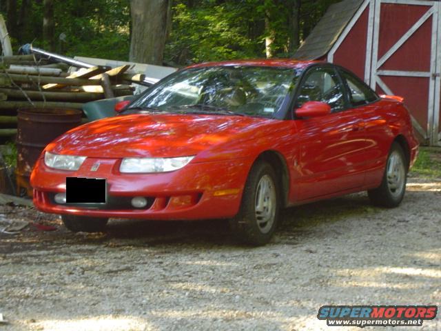 Red 1997 Saturn SC coupe parked in gravel lot