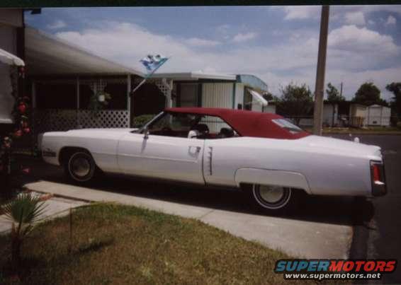 White 1972 convertible with red top parked by a mobile home
