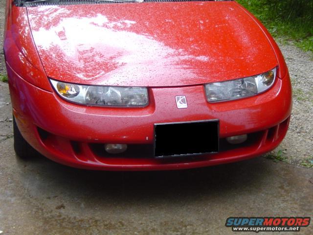 Front view of a red 1997 Saturn SC with water droplets on the hood and body