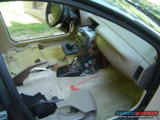 Car interior with seats and carpet removed, showing the dashboard, center console, and floor