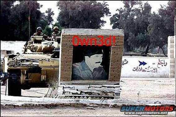 Tank with soldiers and a mural of Saddam Hussein, with "Own3d!" spray-painted over it