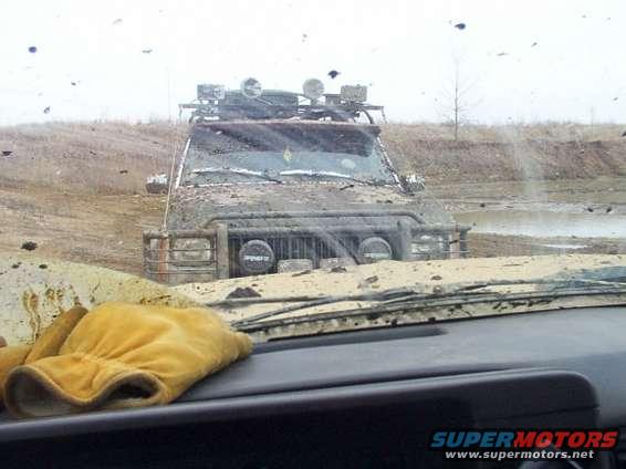 Mud-covered off-road vehicle with roof rack and auxiliary lights