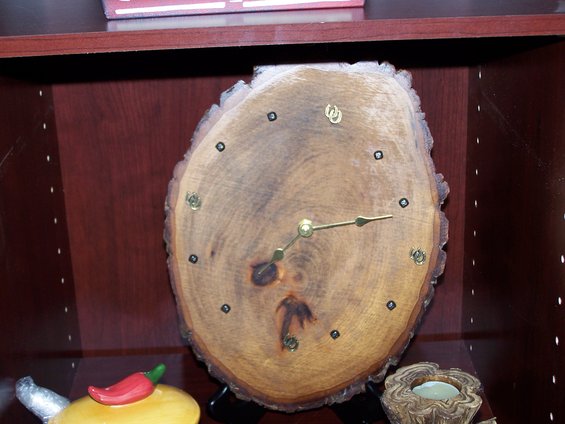 Wood slice clock with brass hands on a shelf