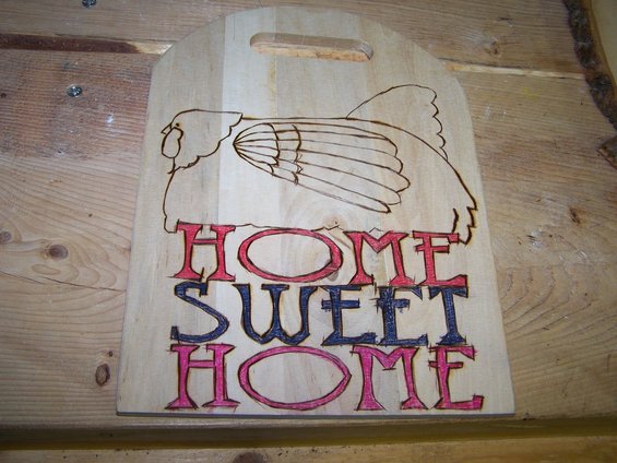 Wooden cutting board with pyrography of a chicken and painted text 'HOME SWEET HOME'