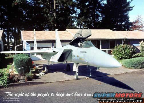 Fighter jet parked in front of a house, canopy open