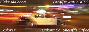 Police car with light streaks, side view. Text reads 'Blake Malecha', 'FordCrownVicDCSO', 'Explorer', 'Dakota Co. Sheriff's Office'