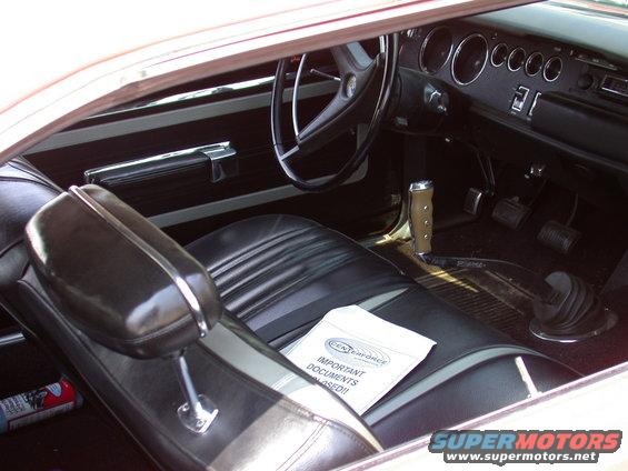 Car interior with black seats, steering wheel, and dashboard. A document labeled 'IMPORTANT DOCUMENTS ENCLOSED!!' is on the passenger seat