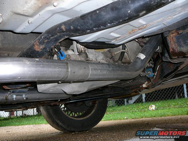 Underneath view of a stainless steel exhaust system with a blue connector