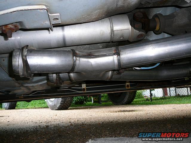 Underside view of a custom exhaust system with a Y-pipe and driveshaft visible