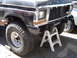 1979 Ford Bronco - Close-up of a 1979 Ford Bronco's front end being worked on, with a second vehicle visible to the side.